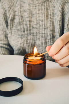 Hand lighting cozy candle with match for relaxation and comfort
