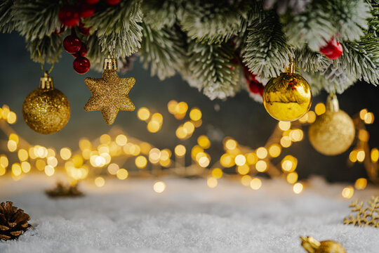 Christmas Holiday background with snow, fir tree and decorations with christmas light behind. Christmas golden balls on a winter festive background.