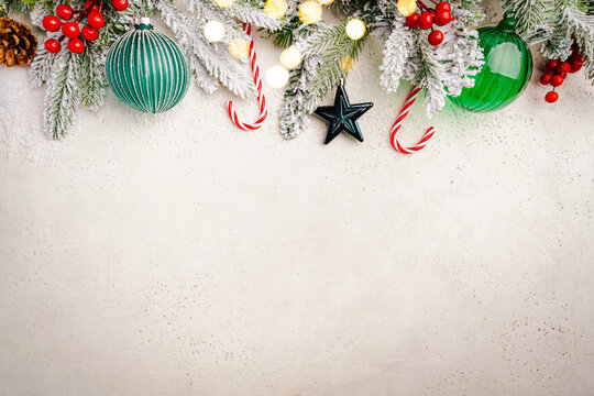 Christmas and New Year background with fir branches with green holiday decorations and pine cones on a white table, banner for holiday screen, template for design. Holiday card