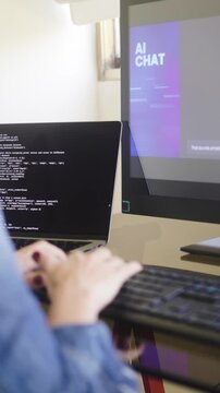 Young adult coding at desk with ai chat interface