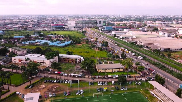 26 September 2026, Lagos Nigeria: An aerial photo of a sprawling urban landscape, featuring a busy highway lined with yellow buses, cars, and commercial vehicles alongside a railway track. 