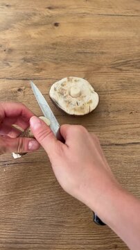 Slicing spoiled wormy wild birch bolete (koźlarz) mushroom with a knife on wooden background. Ideal B-roll for mushroom inspection, foraging tips and bad harvest concept. 9:16 vertical video.