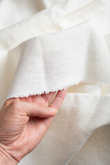 Fototapeta premium Hand Holding Off White Linen Fabric Edge