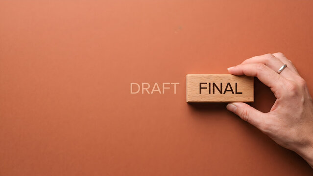 Signifying the successful culmination of a project a hand places the 'FINAL' block, marking the transition from an initial draft to completion and a crucial decision point