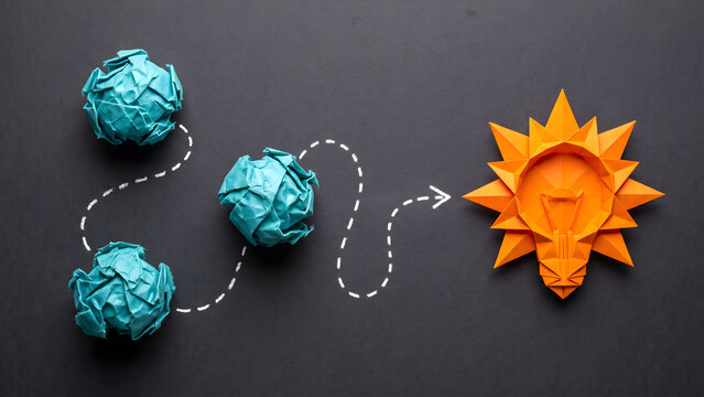 Creative process and innovation concept featuring crumpled blue paper balls leading to an orange origami light bulb on dark background
