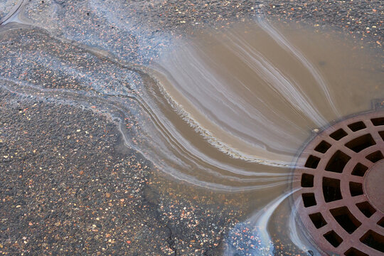 Drain With Water and Debris on a City Street After Rainfall