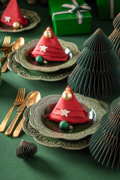 Bottle green table display with holiday ornaments.