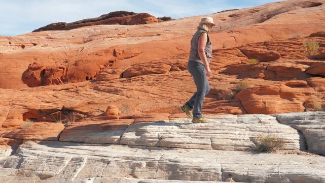 Female hiker walking on white and red sandstone geological formations in valley of fire state park, a popular tourist destination for its stunning natural scenery and unique landscapes