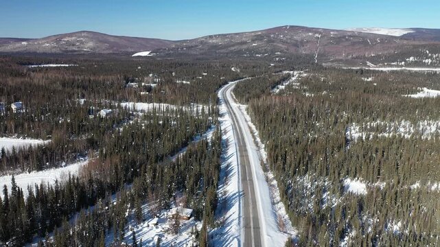 Drone Tracking Shot of Lone Vehicle Navigating Scenic Winter Mountain Highway