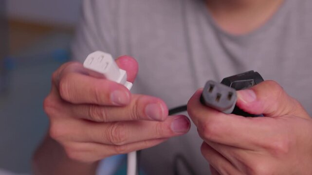 Hands aligning two electrical plug adapters for connection