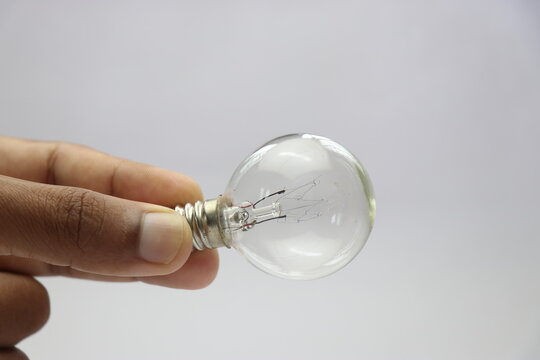View of incandescent bulb with screw type base held in the hand
