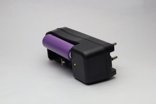 Portable lithium ion battery charger with cell inserted and LED indicator light on white background