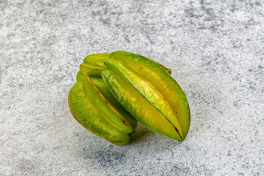 Green star fruit slices arranged on textured gray surface showing natural ridges and yellow undertones