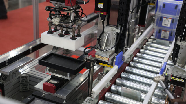 An automated vacuum gripper system handles material components on an industrial conveyor line.
