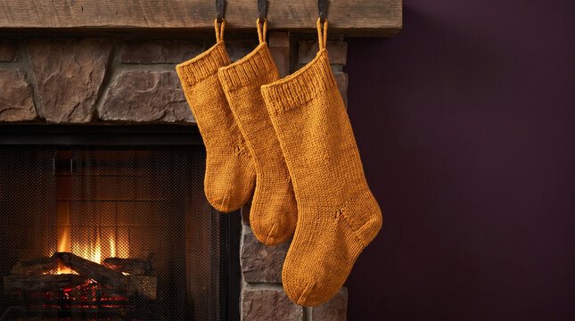 Cozy fireplace with three knitted Christmas stockings hanging  