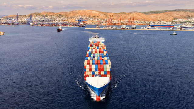 Aerial drone drone point of view photo above huge fully loaded container ship with colorful containers overlooking deep blue sea near logistics port
