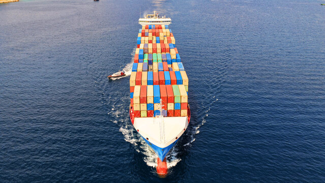 Aerial drone drone point of view photo above huge fully loaded container ship with colorful containers overlooking deep blue sea near logistics port