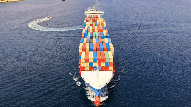 Aerial drone drone point of view photo above huge fully loaded container ship with colorful containers overlooking deep blue sea near logistics port