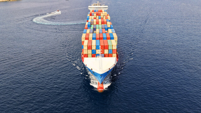 Aerial drone drone point of view photo above huge fully loaded container ship with colorful containers overlooking deep blue sea near logistics port