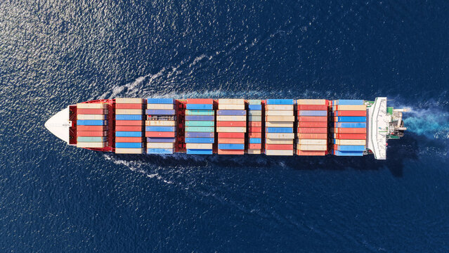Aerial drone top down photo above huge size container ship cruising deep blue Mediterranean sea