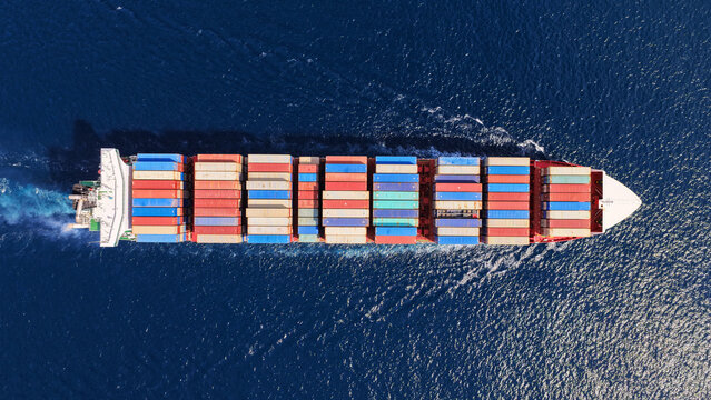 Aerial drone drone point of view photo above huge fully loaded container ship with colorful containers overlooking deep blue sea near logistics port