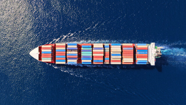 Aerial drone drone point of view photo above huge fully loaded container ship with colorful containers overlooking deep blue sea near logistics port