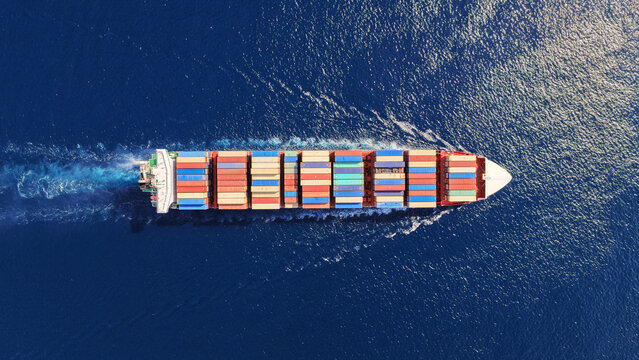 Aerial drone top down photo above huge size container ship cruising deep blue Mediterranean sea