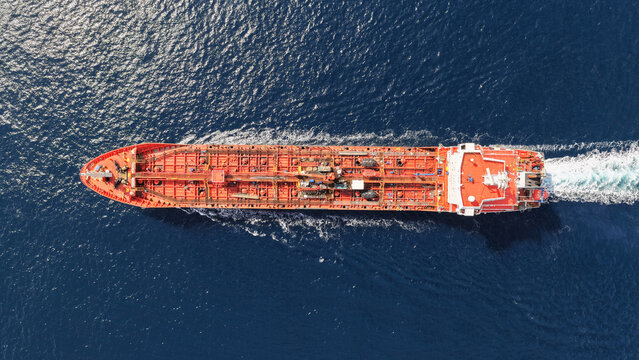 Aerial drone top down photo of small oil - chemical tanker cruising in deep blue open ocean sea