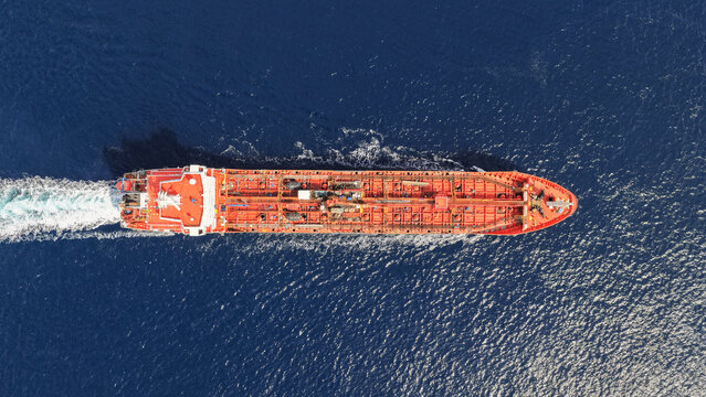 Aerial drone top down photo of small oil - chemical tanker cruising in deep blue open ocean sea