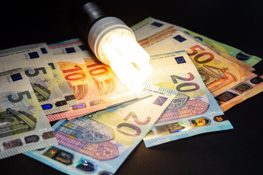 light from light bulb on cash euro banknotes as price for electricity, total blackout or saving, utility tariffs, bills, subsidies in europe energy market. filter image