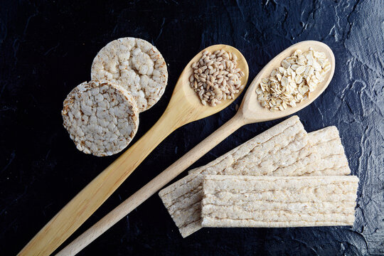 Healthy whole grain crispbreads and various seeds in wooden spoons  background. Healthy eating, diet food and weight loss concept.