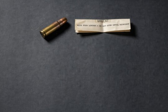 Brass bullet and secret folded message on dark background, criminal threat concept, dramatic ransom note layout