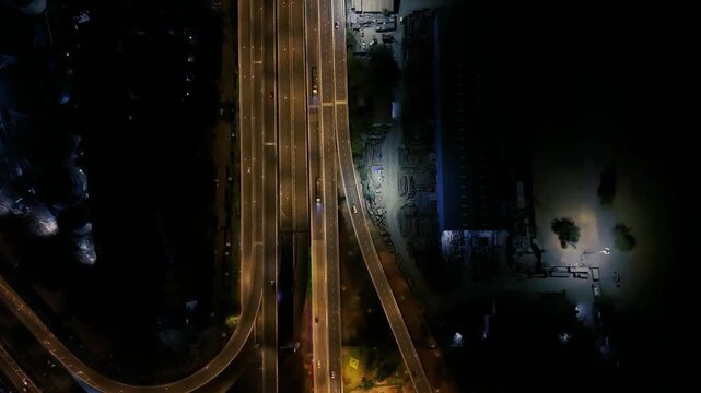 Cinematic top-down drone footage of Atal Setu, Mumbai Trans Harbour Link, showing illuminated multi-lane highways, moving traffic and connecting road ramps at night.