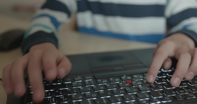 Close-up children's hands typing on laptop computer keyboard. 4K 10-bit