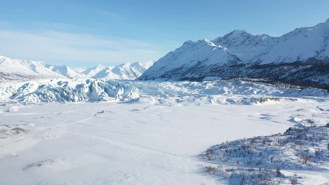Low Pass Over Glacial Crevasses Revealing Dramatic Sunlit Mountain Peaks