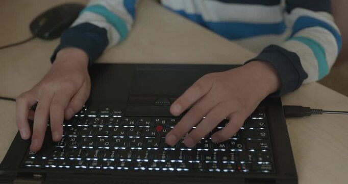 Close-up children's hands typing on laptop computer keyboard. 4K 10-bit