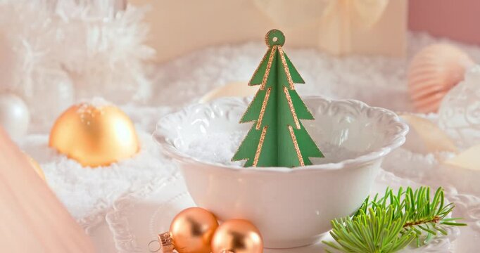 White holiday table setup with baubles, ornaments, and snow.