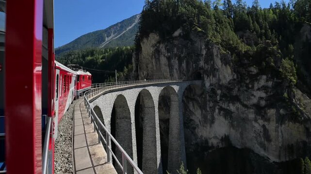 Davos, Switzerland - 06.09.2026: Red train travels across the historic Landwasser Viaduct in the Swiss Alps.