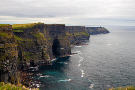 Majestic sea cliffs and turquoise waters of Cliffs of Moher stretching along the Atlantic coastline, County Clare, Ireland.