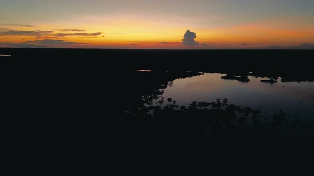 Dramatic Dusk Over Flooded Amazon Rainforest in Ecuador, Orange Horizon, Dark Lagoon, Tree Islands and Remote Tropical Wetland Wilderness