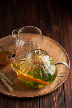 Invigorating herbal tea in a glass teapot with fresh lemon slices and mint leaves