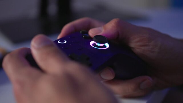 Adult man reacting with game controller during intense gameplay at glowing PC desk, side view with colorful RGB light reflections and focused expression