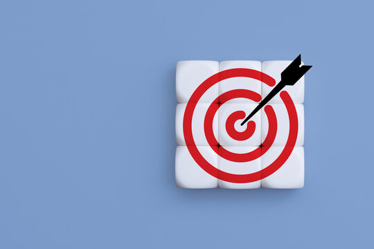 Red target with arrow hitting bullseye printed on white cubes grid over blue background. Strategic goal achievement, marketing target focus, objective accuracy and business success concept.