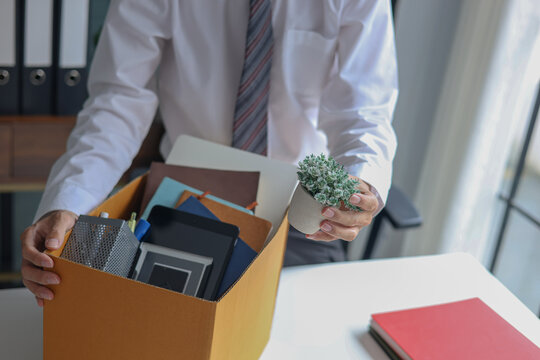 Male employee packing office desk items into box after job termination or resignation.