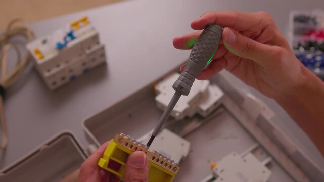 Electrician testing wires with multimeter in control box; close-up industrial style, safety and maintenance concept, ideal for engineering, construction, service, training and technical visuals