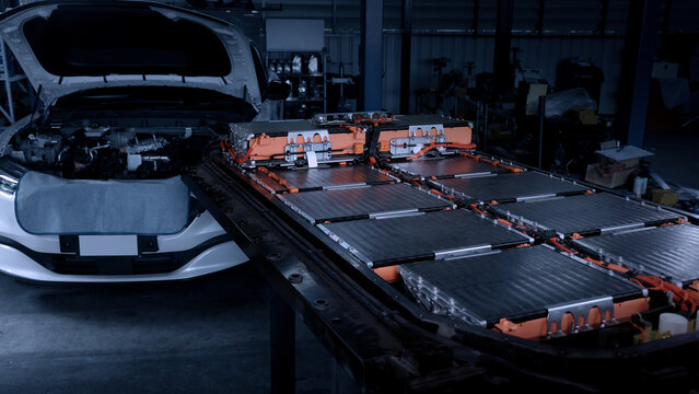 EV car service. Electric vehicle battery pack being serviced or inspected in automotive workshop. Large battery modules and high voltage components. Modern EV power systems. Lithium ion NMC NCA or LFP