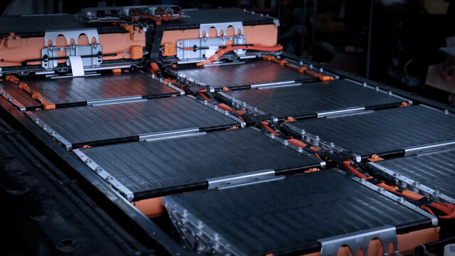 EV car service. Electric vehicle battery pack being serviced or inspected in automotive workshop. Large battery modules and high voltage components. Modern EV power systems. Lithium ion NMC NCA or LFP