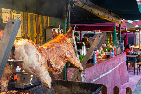 Whole spit roasted pig at an outdoor culinary market, concept of traditional rustic feast and slow cooking.