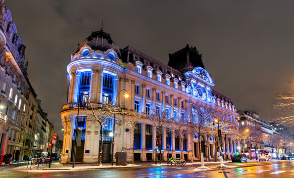 Historic neoclassical architecture on Boulevard des Italiens illuminated at night in Paris, France.