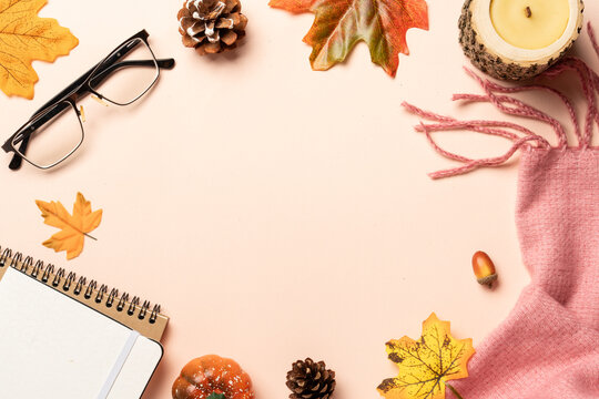 Autumn flat lay background. Autumn leaves, notepad, scarf, candle and spices on yellow background.